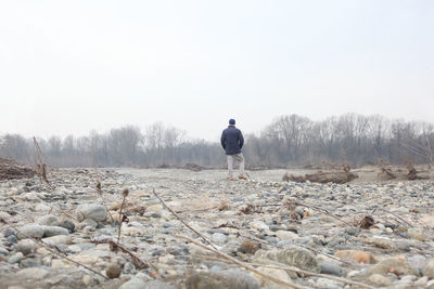 Rear view of man standing on field against sky