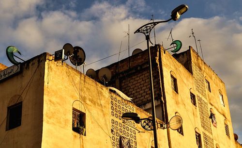 Low angle view of street light by building against sky