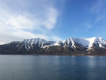 Scenic view of snowcapped mountain by sea against sky