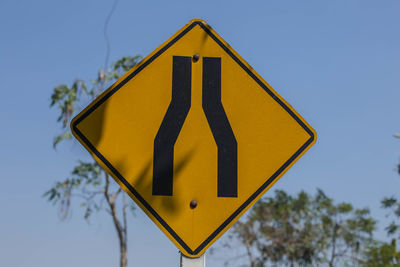 Close-up of road sign against blue sky