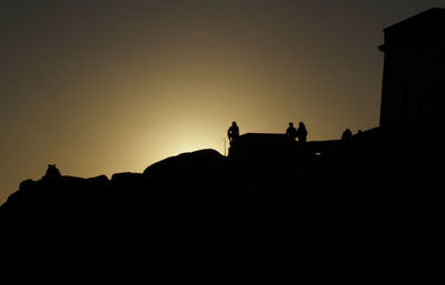 Silhouette people against clear sky at sunset