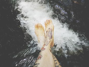 Low section of woman sitting on river