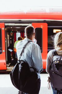 Rear view of couple with backpacks waiting at railroad station