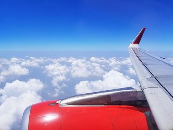 Cropped image of aircraft wing flying against blue sky