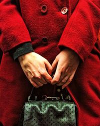 Midsection of woman in red coat while holding purse