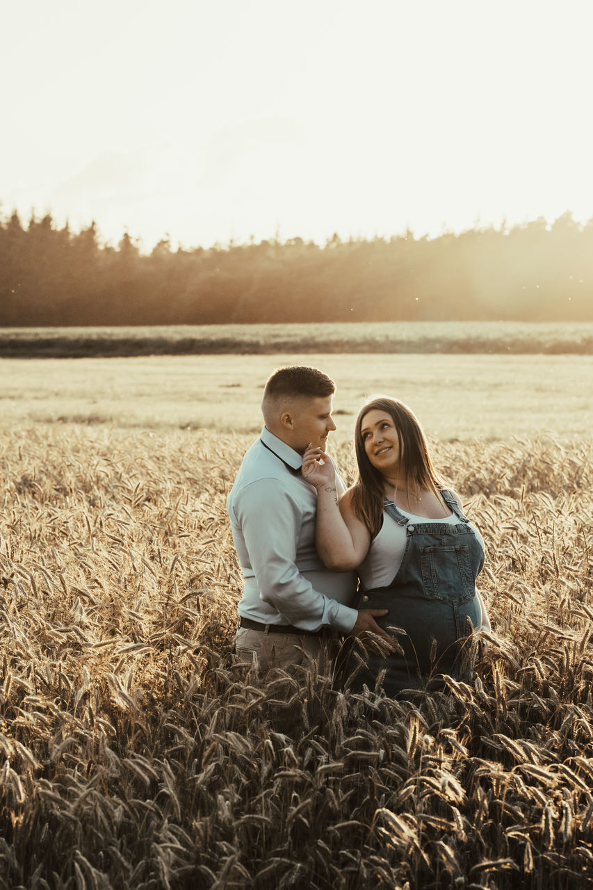 togetherness, adult, two people, women, emotion, positive emotion, love, field, sky, nature, landscape, rural scene, land, men, bonding, plant, happiness, young adult, romance, female, smiling, agriculture, copy space, sunlight, tranquility, affectionate, embracing, crop, lifestyles, environment, casual clothing, summer, morning, relaxation, sitting, enjoyment, leisure activity, beauty in nature, cereal plant, child, day, grass, farm, tranquil scene, outdoors, back lit, lens flare, simple living, person, idyllic, cheerful, wheat, portrait