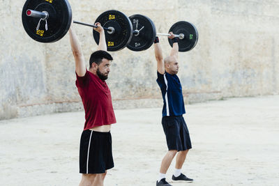 Two weightlifters lifting weights in an urban environment.