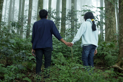 Rear view of people standing in forest