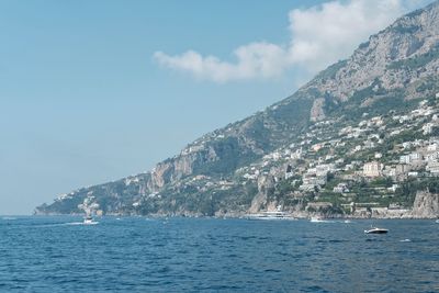 Scenic view of sea by mountains against sky