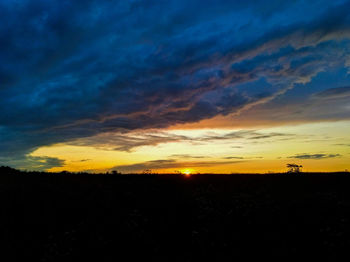 Silhouette landscape against dramatic sky during sunset