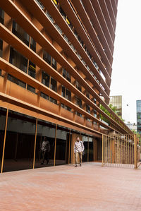 Rear view of man walking against building in city