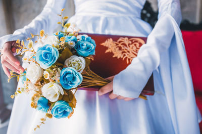 Midsection of woman holding book and flowers
