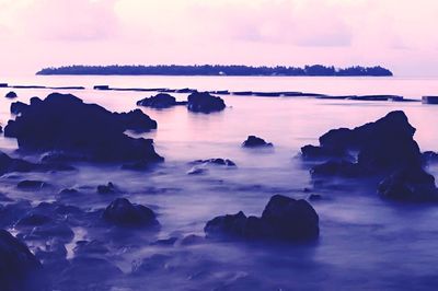 Rocks in sea at sunset