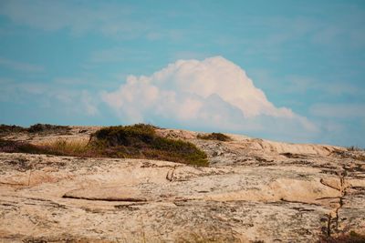 Scenic view of arid landscape against cloudy sky