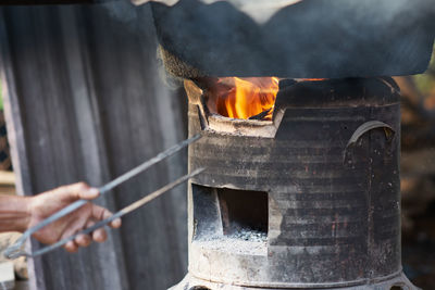 Man holding burning firewood on wood