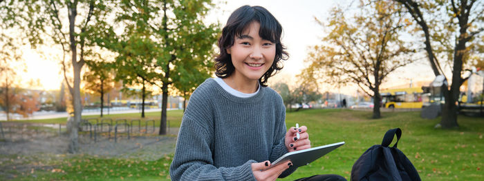 Portrait of young woman sitting on field