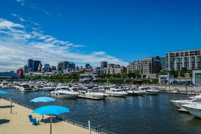 Sailboats moored in sea against buildings in city