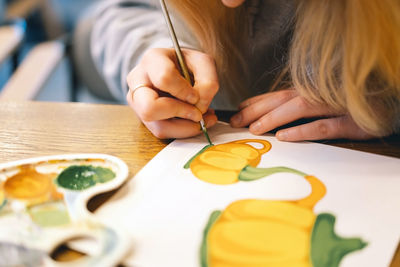 Pretty teenage girl draws a picture with poster paint.