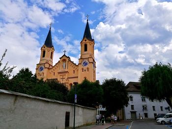 Church amidst trees and buildings against sky