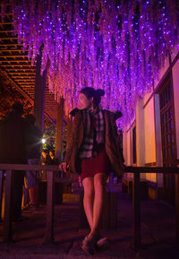Full length of woman standing against illuminated building at night