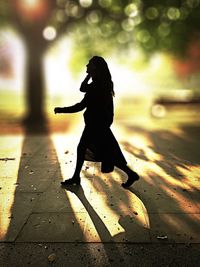 Close-up of silhouette woman walking on road