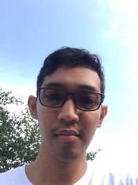 Portrait of young man wearing eyeglasses against sky