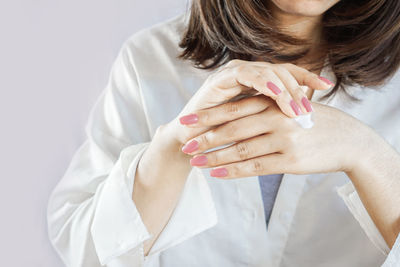 Close-up of woman holding hands over white background