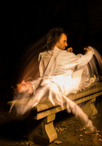 Multiple exposure image of man sitting on bench outdoors