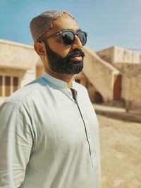 Portrait of young man wearing sunglasses against wall