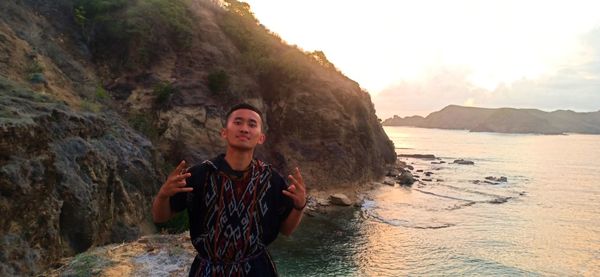 Young man standing by sea against sky