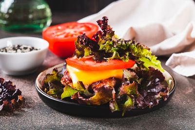 Spicy keto burger on fresh lettuce leaves of cutlet, tomato and cheese on a plate on the table