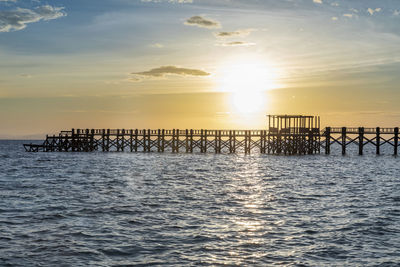 Pier over sea against sky during sunset