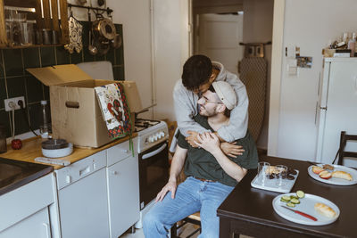 Romantic man embracing boyfriend in kitchen at home