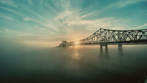 Bridge over sea against sky during sunset