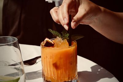 Cropped hand of woman having drink in restaurant