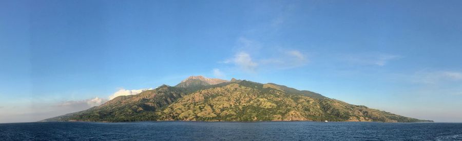 Scenic view of sea and mountains against blue sky