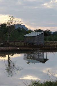 Reflection of building in lake against sky during sunset