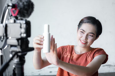 Portrait of a smiling young woman holding camera