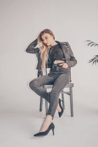 Portrait of young woman sitting on floor against white background