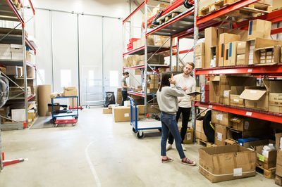 Coworkers examining while standing at warehouse