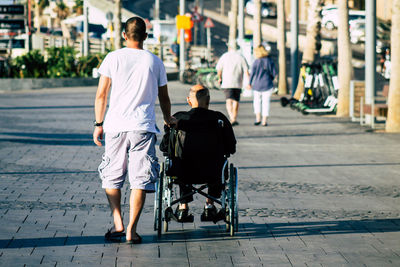 Rear view of men walking on street in city