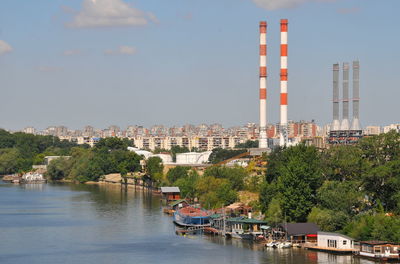 Buildings by river against sky in city