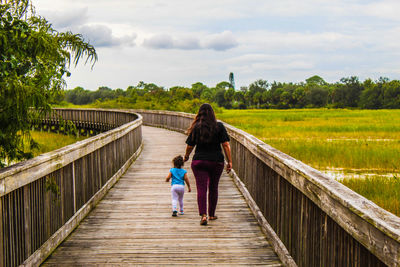 Rear view of woman and child walking on footbridge