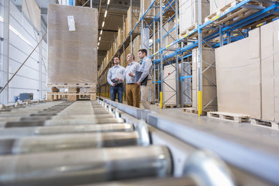 Three men talking in factory warehouse