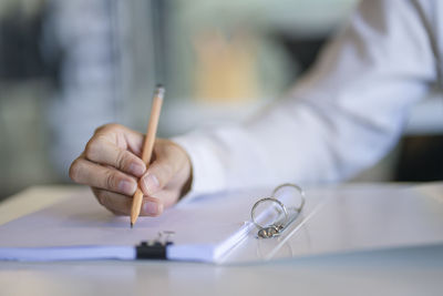 Close-up of hand holding paper on table