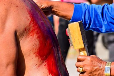 Cropped hands holding blade by injured man during festival