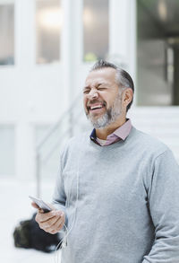 Businessman laughing while communicating through headphones in office