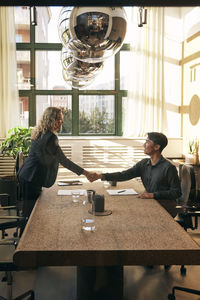 Side view of woman sitting on table