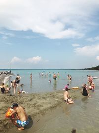 People enjoying at beach against sky