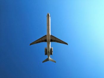 Directly below shot of airplane against clear blue sky